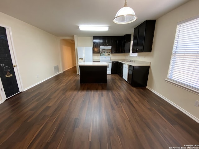 kitchen featuring a kitchen island, decorative light fixtures, sink, dark wood-type flooring, and white appliances