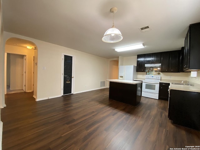 kitchen featuring sink, hanging light fixtures, a center island, dark wood-type flooring, and white appliances