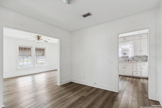 unfurnished room with dark wood-type flooring, ceiling fan, ornamental molding, and sink