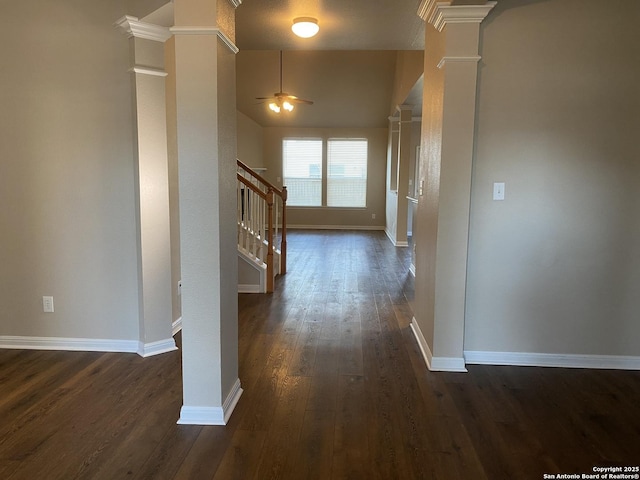 corridor with dark wood finished floors, decorative columns, stairway, and baseboards