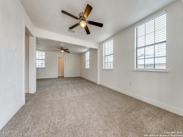 carpeted empty room featuring a wealth of natural light and ceiling fan