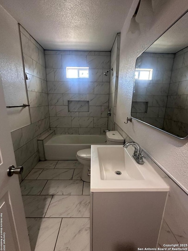 full bathroom with tiled shower / bath, vanity, toilet, and a textured ceiling