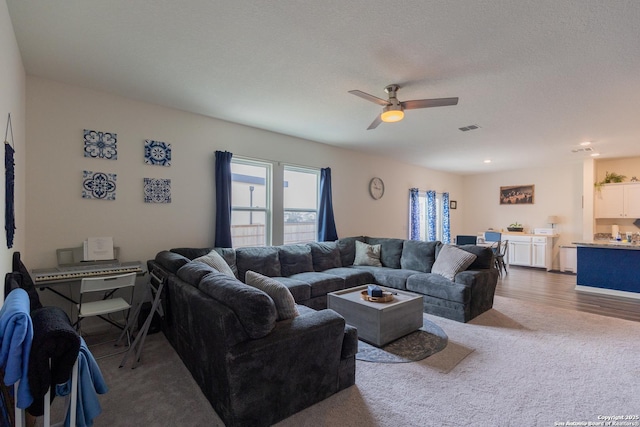 living room with wood-type flooring, a textured ceiling, and ceiling fan