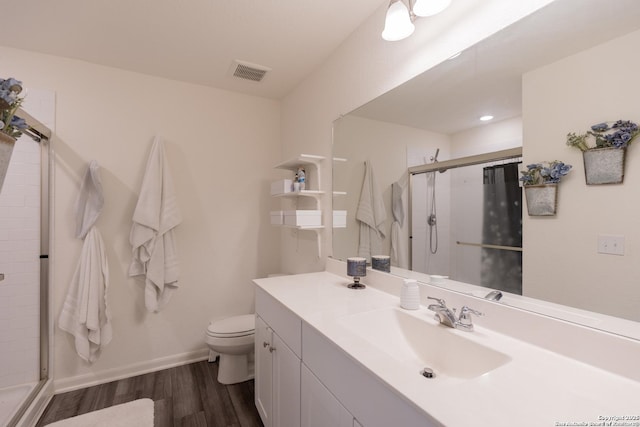 bathroom featuring vanity, toilet, a shower with shower door, and hardwood / wood-style floors