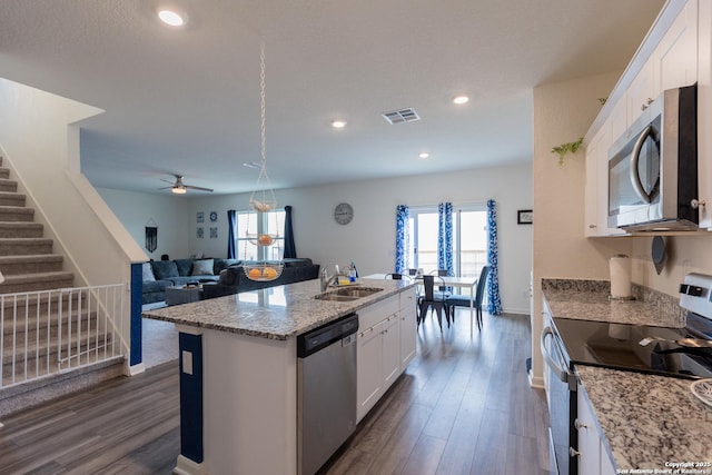 kitchen with appliances with stainless steel finishes, white cabinetry, sink, dark hardwood / wood-style flooring, and a kitchen island with sink