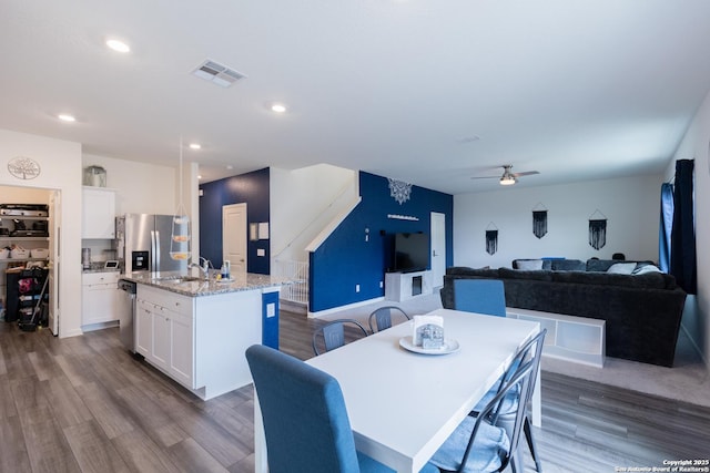 dining area with ceiling fan, sink, and dark hardwood / wood-style flooring