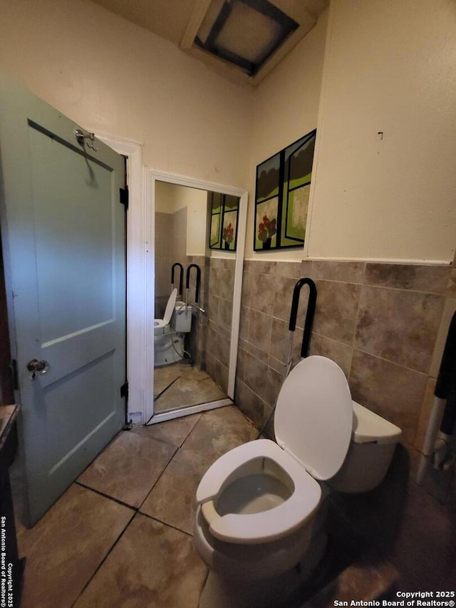 bathroom featuring tile patterned flooring, toilet, and tile walls