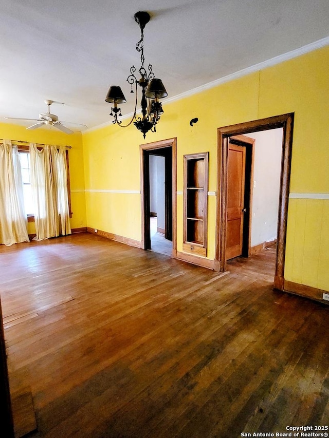 unfurnished room with crown molding, ceiling fan with notable chandelier, and dark hardwood / wood-style flooring