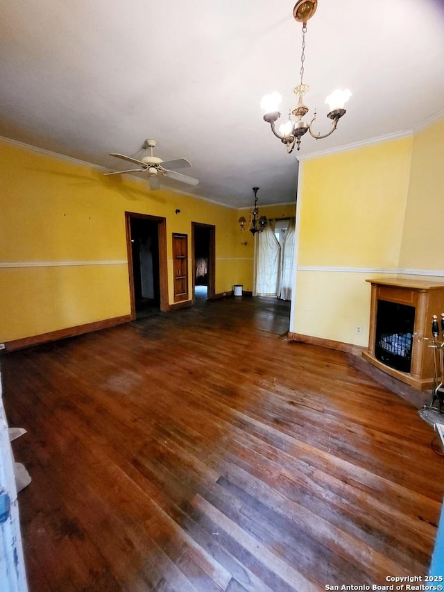 unfurnished living room with dark hardwood / wood-style flooring, crown molding, a fireplace, and ceiling fan with notable chandelier