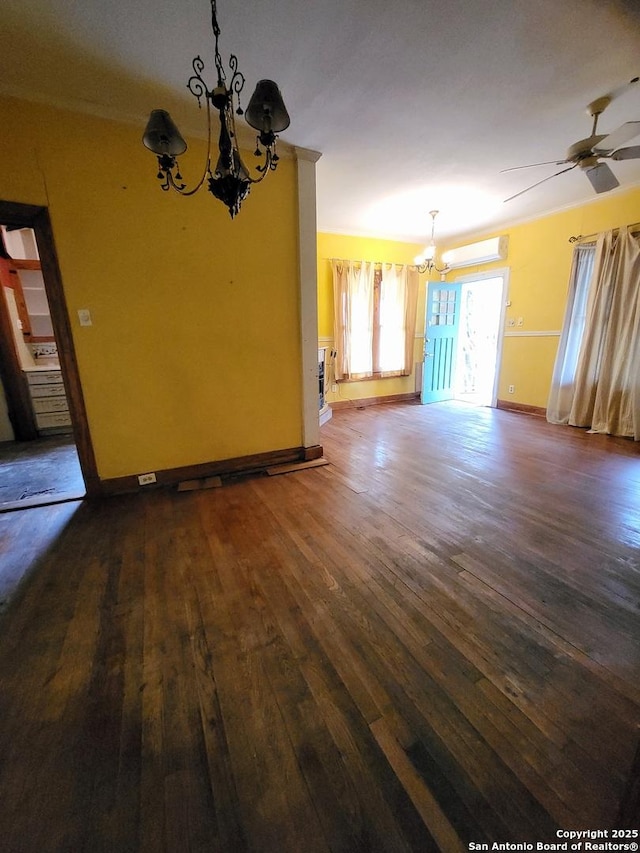 unfurnished room featuring an AC wall unit, ceiling fan with notable chandelier, and dark hardwood / wood-style floors