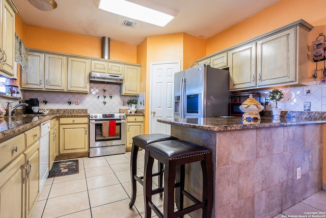 kitchen with a kitchen bar, sink, light tile patterned floors, appliances with stainless steel finishes, and decorative backsplash