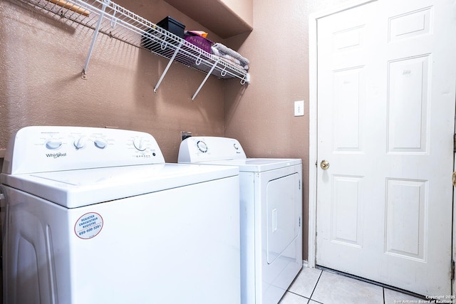 clothes washing area with washer and dryer and light tile patterned floors