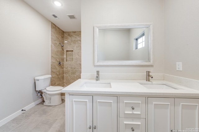 bathroom featuring vanity, toilet, and a tile shower