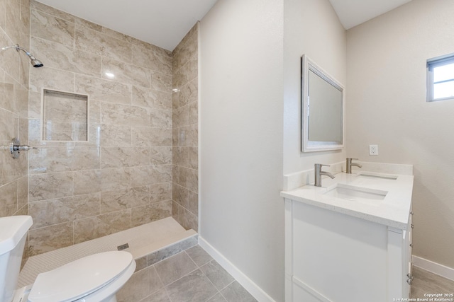 bathroom with vanity, toilet, and a tile shower