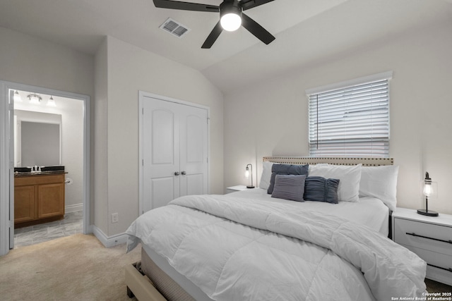 carpeted bedroom with ceiling fan, lofted ceiling, ensuite bathroom, and a closet