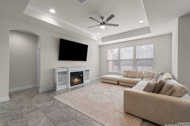 living room with ceiling fan and a tray ceiling