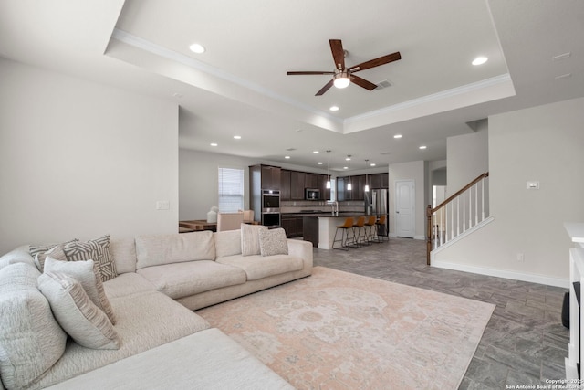 living room featuring crown molding, ceiling fan, and a raised ceiling