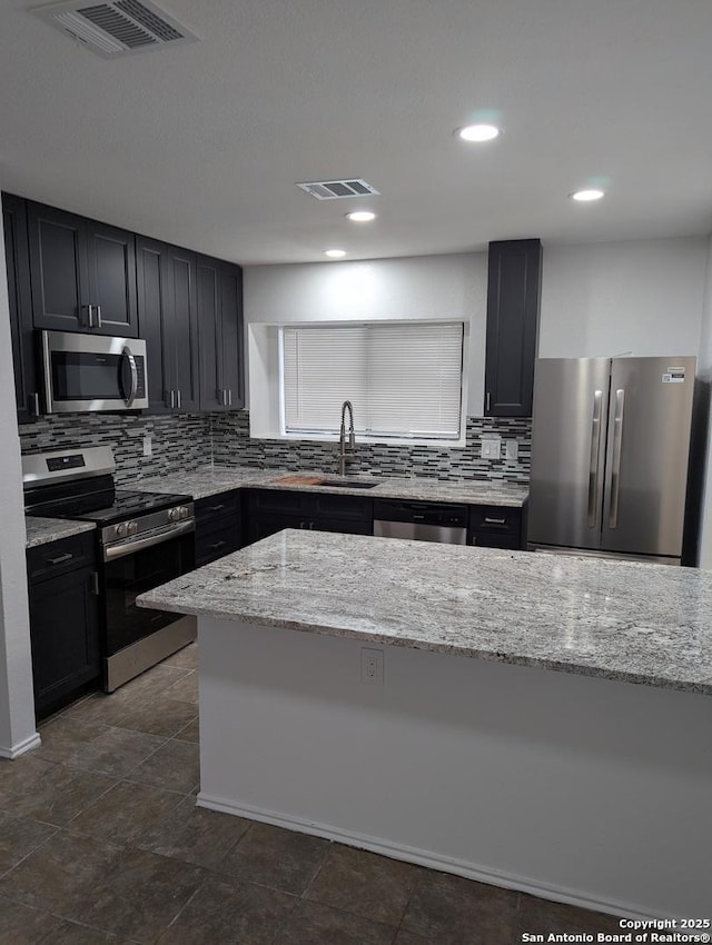 kitchen featuring light stone counters, sink, tasteful backsplash, and appliances with stainless steel finishes