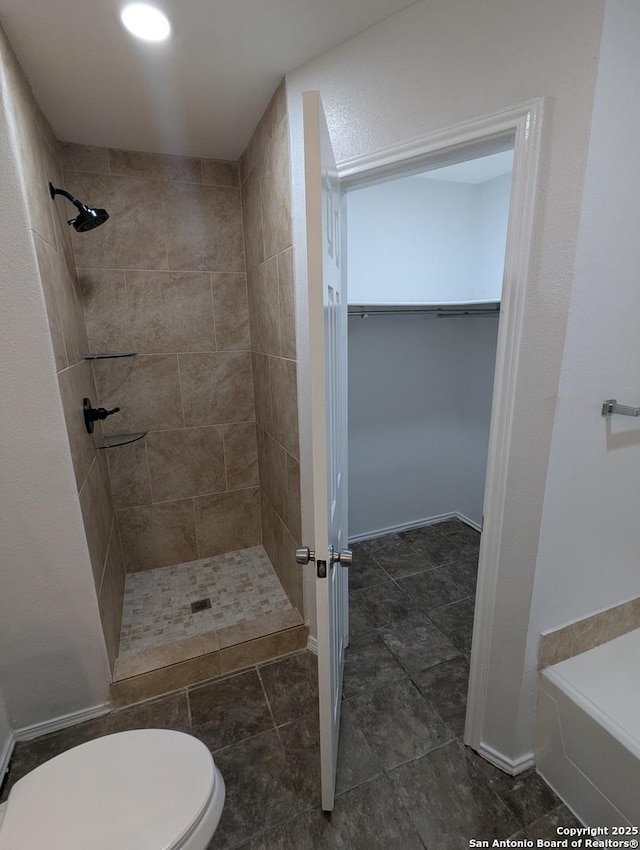 bathroom with tiled shower and toilet