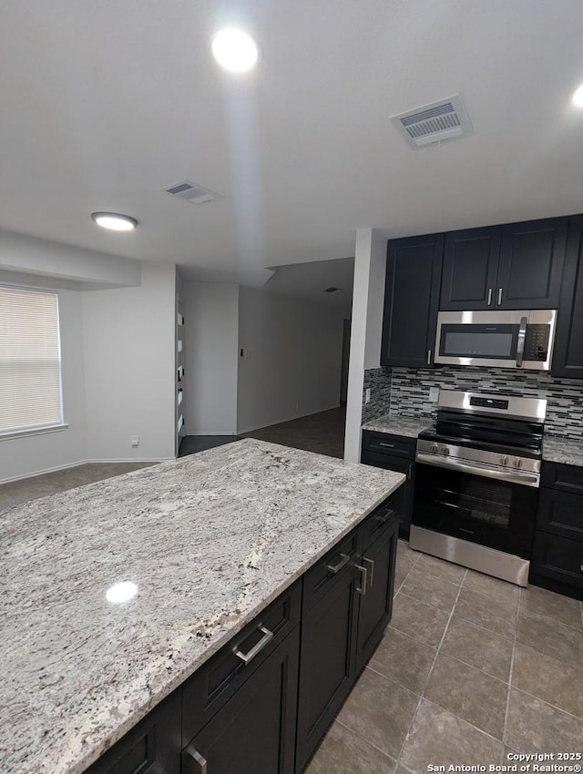 kitchen featuring light stone counters, appliances with stainless steel finishes, and backsplash