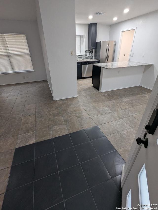 kitchen featuring backsplash, a kitchen breakfast bar, stainless steel appliances, light stone countertops, and kitchen peninsula