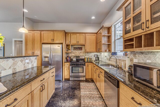 kitchen featuring sink, dark stone countertops, appliances with stainless steel finishes, pendant lighting, and decorative backsplash