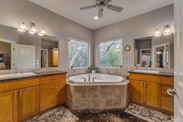 bathroom with vanity, a relaxing tiled tub, and ceiling fan