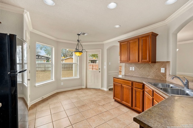 kitchen with sink, crown molding, backsplash, light tile patterned flooring, and black fridge