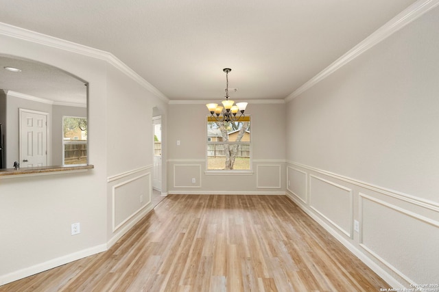 unfurnished dining area with an inviting chandelier, ornamental molding, and light wood-type flooring