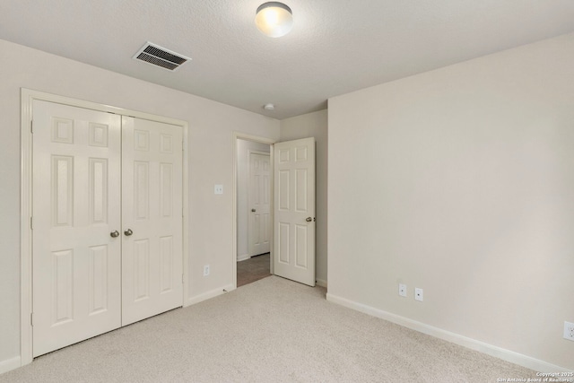 unfurnished bedroom with a closet, light carpet, and a textured ceiling