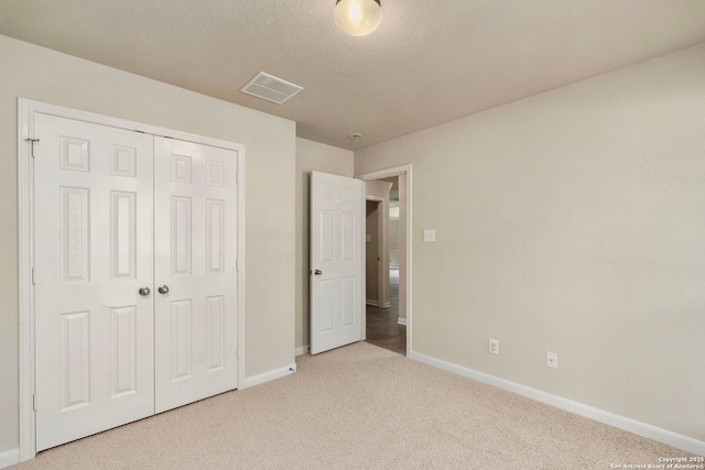 unfurnished bedroom featuring a closet, light carpet, and a textured ceiling