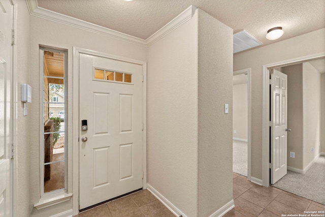 entrance foyer featuring light tile patterned flooring, ornamental molding, and a textured ceiling