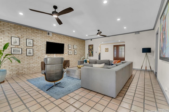 living room with ornamental molding, ceiling fan, and brick wall