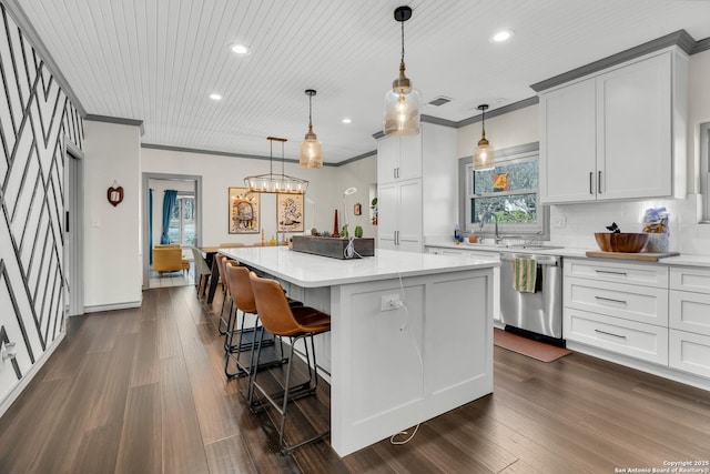 kitchen featuring white cabinetry, crown molding, decorative light fixtures, stainless steel dishwasher, and a kitchen island