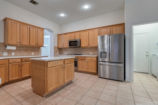 kitchen with appliances with stainless steel finishes, a center island, light tile patterned floors, and backsplash