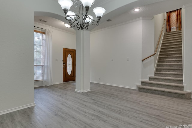 foyer with ornamental molding, a chandelier, and light hardwood / wood-style flooring