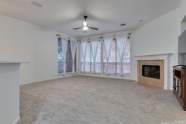 unfurnished living room featuring ceiling fan, light colored carpet, and a tiled fireplace