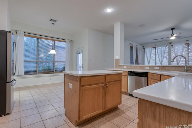 kitchen with appliances with stainless steel finishes, sink, hanging light fixtures, a center island, and light tile patterned floors