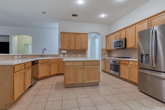 kitchen with appliances with stainless steel finishes, sink, kitchen peninsula, and decorative backsplash