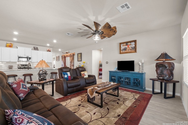 living room featuring sink, light hardwood / wood-style floors, and ceiling fan