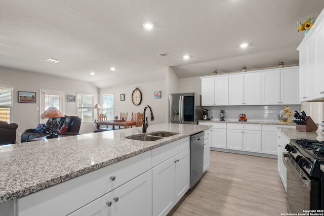 kitchen with sink, white cabinetry, tasteful backsplash, stainless steel appliances, and light stone countertops