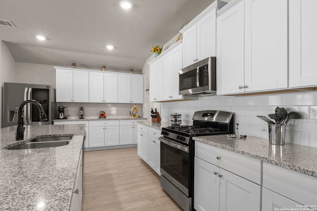 kitchen featuring light stone counters, sink, white cabinets, and appliances with stainless steel finishes