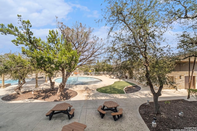 view of home's community with a pool and a patio