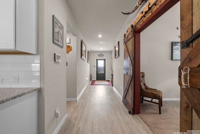 hallway with light hardwood / wood-style floors and a barn door