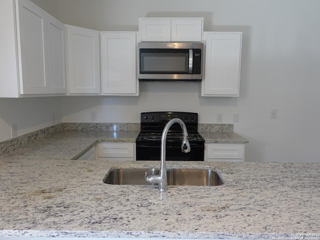 kitchen with light stone counters, black / electric stove, sink, and white cabinets