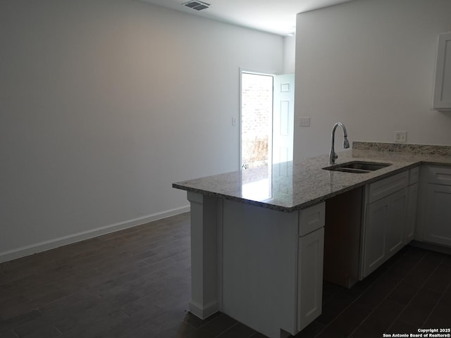 kitchen featuring sink, white cabinets, dark hardwood / wood-style flooring, light stone counters, and kitchen peninsula