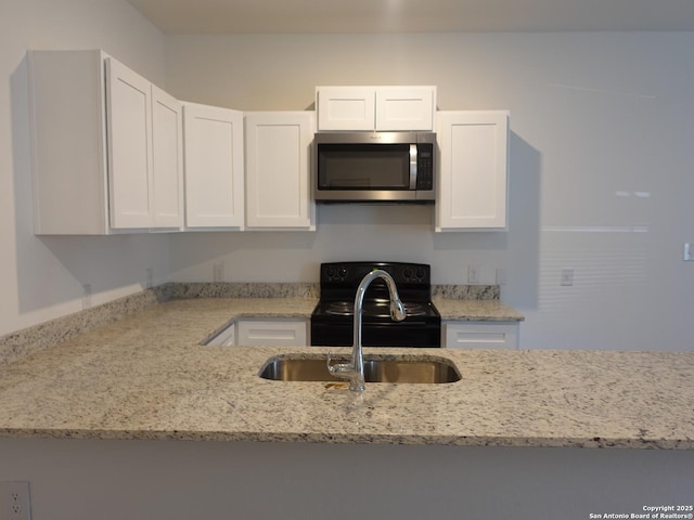 kitchen with light stone counters, black range with electric stovetop, sink, and white cabinets