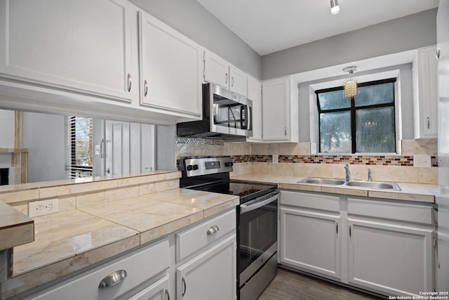 kitchen featuring sink, tasteful backsplash, pendant lighting, stainless steel appliances, and white cabinets