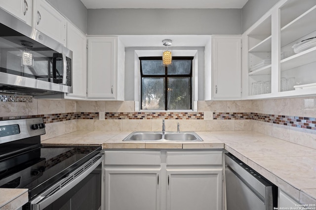 kitchen with sink, appliances with stainless steel finishes, hanging light fixtures, tasteful backsplash, and white cabinets