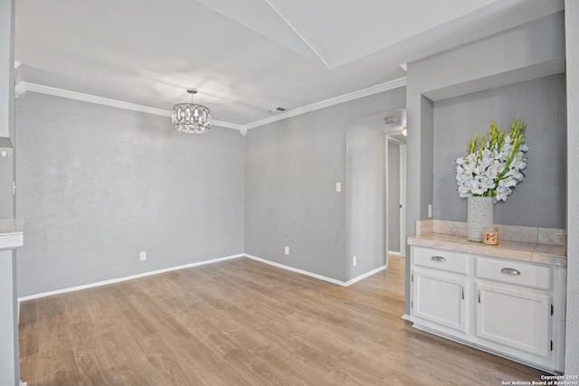 interior space featuring an inviting chandelier, ornamental molding, and light wood-type flooring